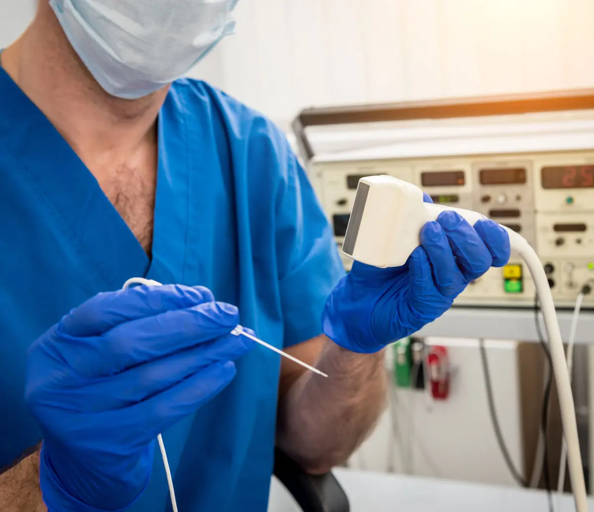 A clinician holds up an electrode and transducer used for ablative procedures