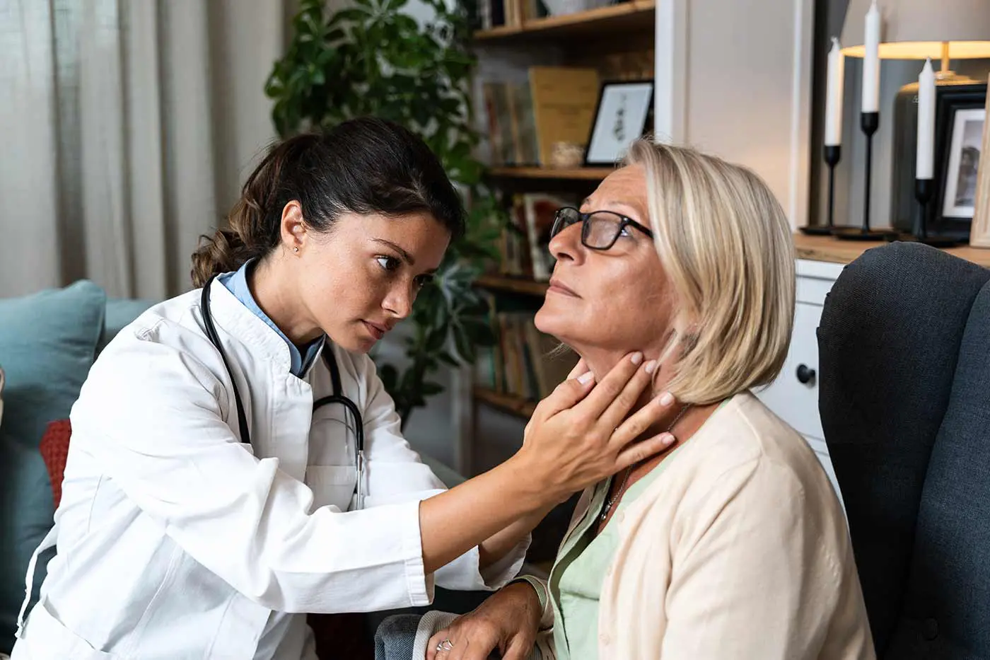 A clinician examines the thyroid of an older patient.