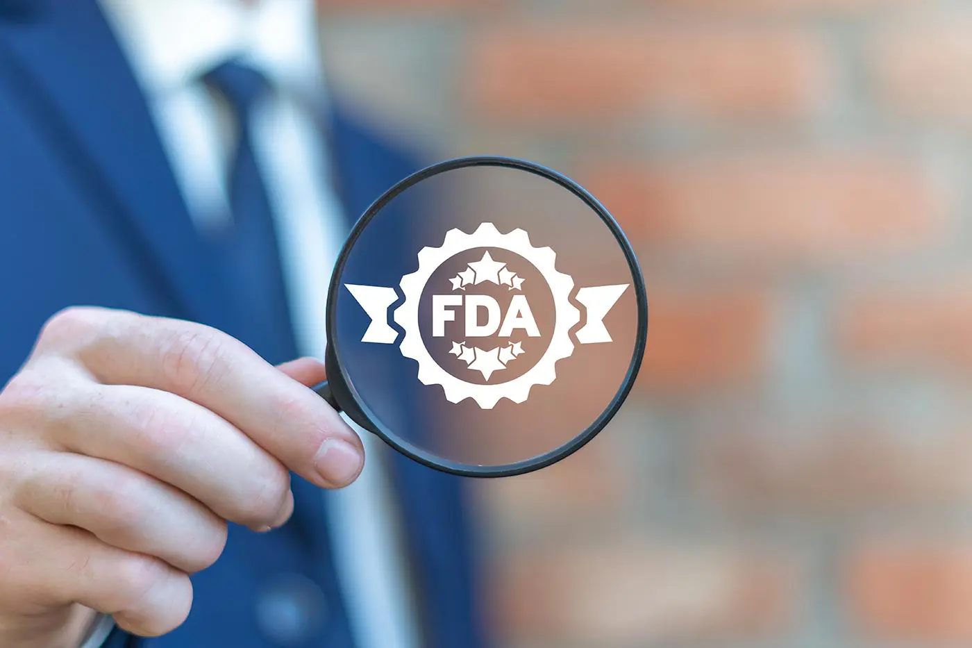 A man holds a magnifying glass with the FDA logo in the center.