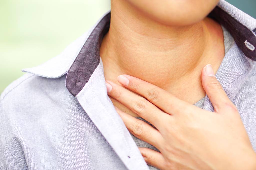 A patient with an abnormal thyroid gland touches their neck with concern.