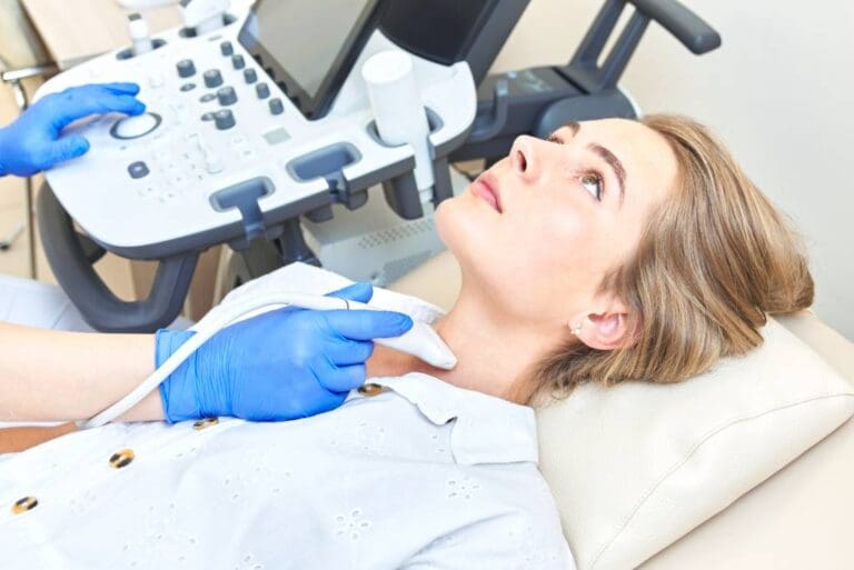A female patient receives an ultrasound of the thyroid.
