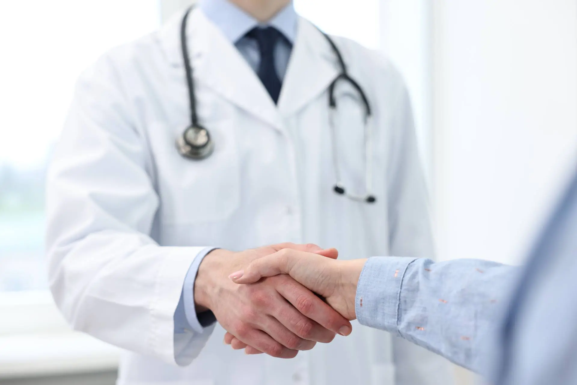 A doctor shakes hands with a new patient.