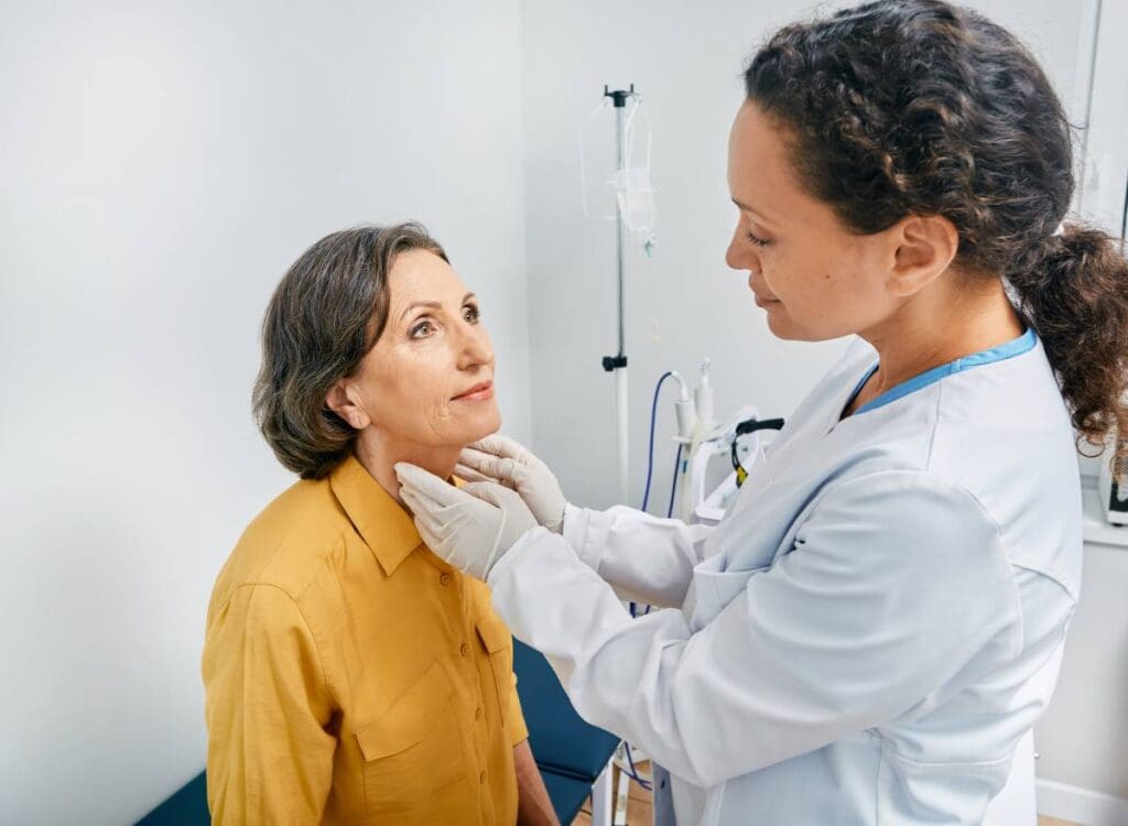 A clinician palpates a patient’s thyroid.