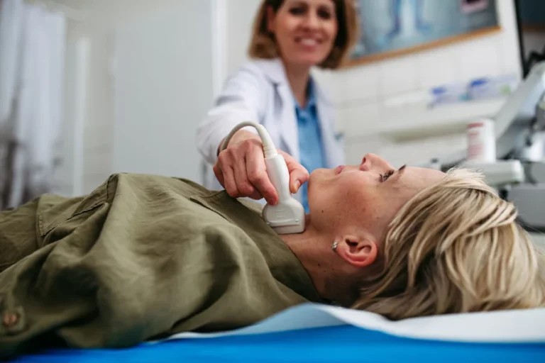 A doctor smiles while performing an ultrasound following successful RFA treatment for thyroid.