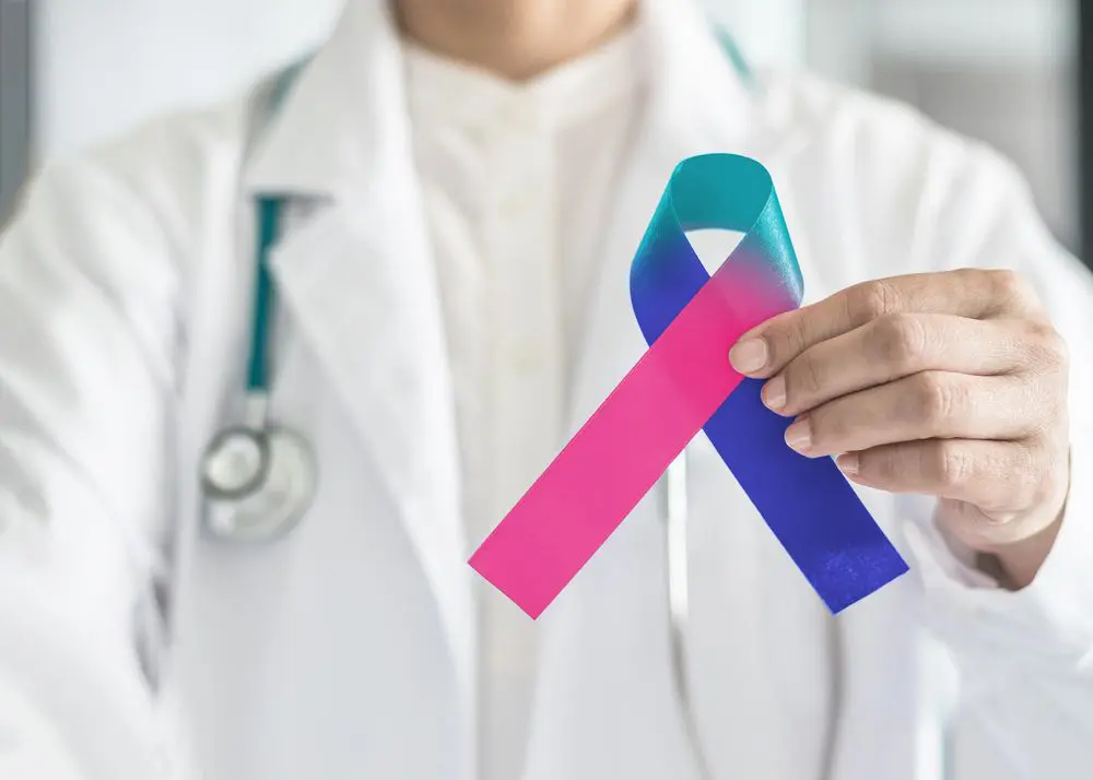 A clinician holds up a thyroid cancer awareness ribbon.
