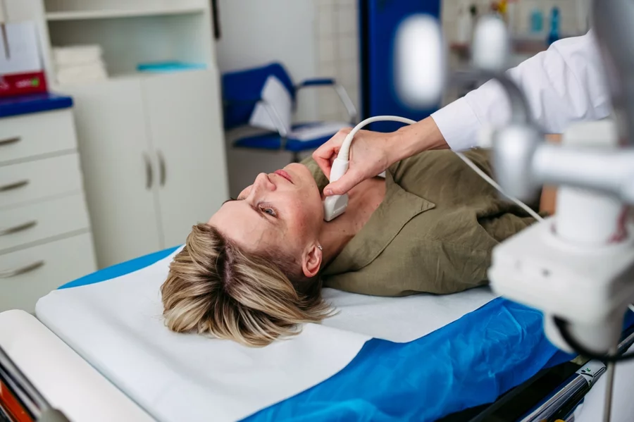 A female patient undergoes a thyroid ultrasound examination.