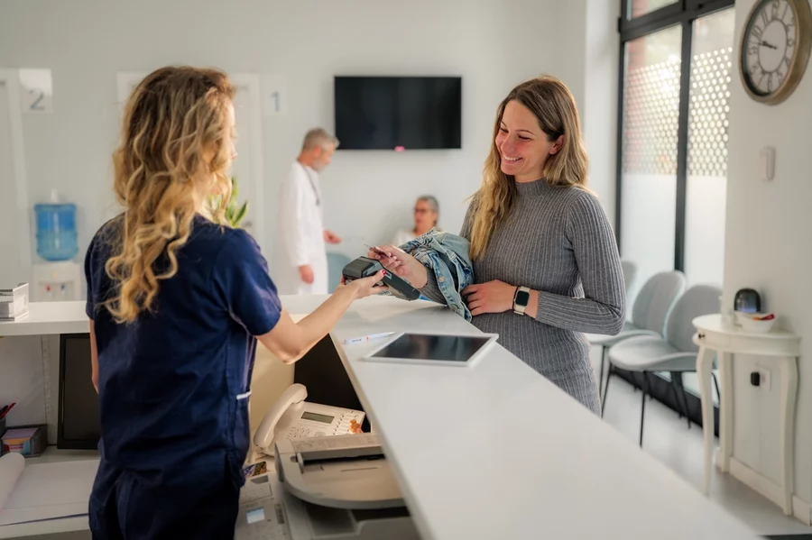 A patient shows a provider her insurance card while checking in to a medical clinic.