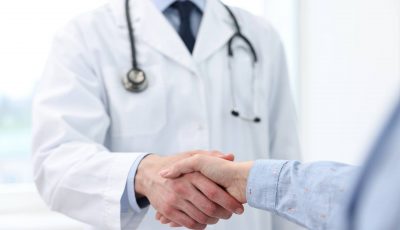 A doctor shakes hands with a new patient.
