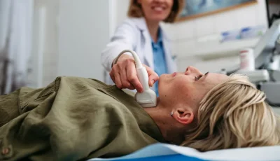 A doctor smiles while performing an ultrasound following successful RFA treatment for thyroid.