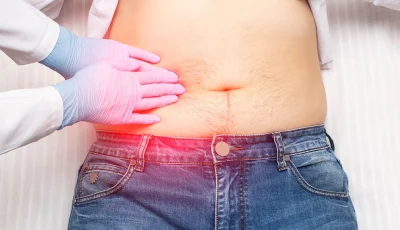 A clinician palpates a patient’s abdomen.