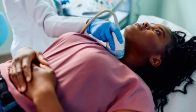 A clinician performs a thyroid ultrasound on a female patient.