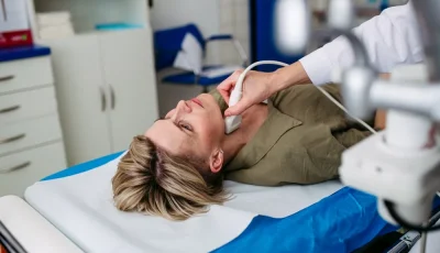 A clinician performs a thyroid ultrasound on a prostrate patient.
