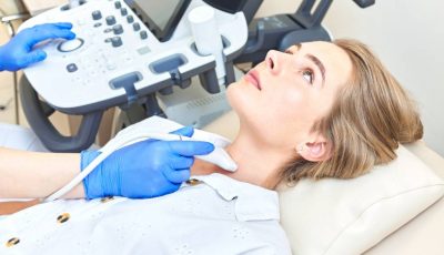 A female patient receives an ultrasound of the thyroid.