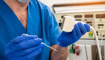 A clinician holds up an electrode and transducer used for ablative procedures