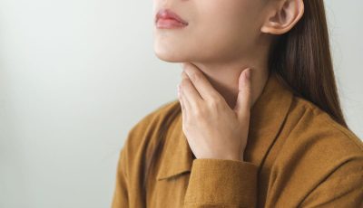 A young woman touches her neck over her thyroid